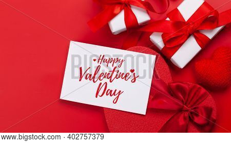 Valentines day greeting card. Gift boxes and heart shaped decor over red background. Top view flat lay