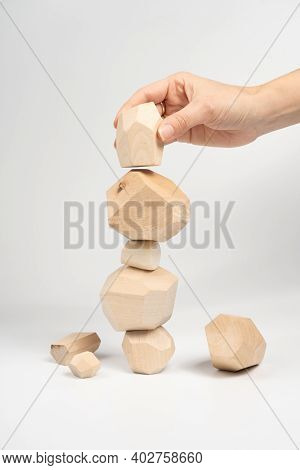 Tumi-ishi Puzzle Game. A Woman Or A Girl Places Her Hand On Another Block Of Wood On Top Of An Unsta