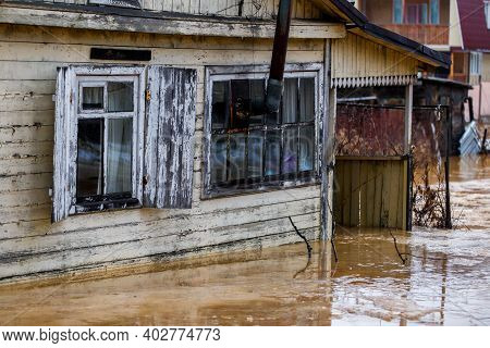 Ecological Catastrophy. The Stream Of A Dirty Brown River Flows Along The Ground In A Holiday Villag