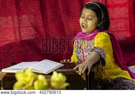An Indian Cute Girl Child Singing And Playing Harmonium In Ethnic Dress