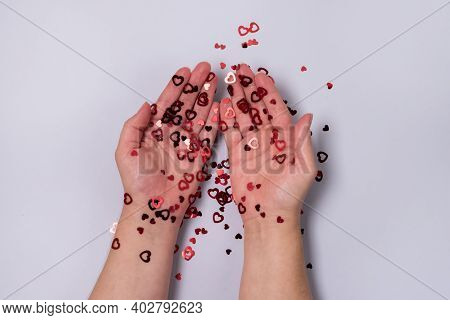 Female Hands With Vibrant Red Sparkling Heart Shaped Confetti On Light Blue Background Flat Lay Vale