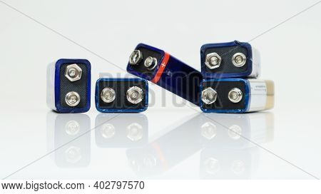 Five Blue Used, Chaotically Laid Out And Scattered Pp3 Batteries On A White Background With Reflecti