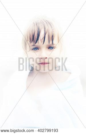 A Beautiful Little Angel Girl With Fathomless Blue Eyes. Portrait Of An Innocent Child In A White Ha
