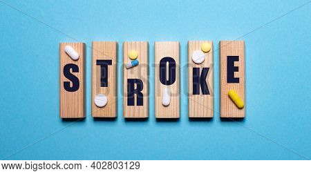 On A Blue Background, Wooden Blocks With The Word Stroke And Pills. Medical Concept