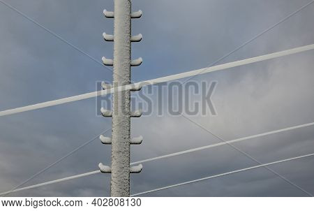 Power Lines Frozen By A Large Layer Of Ice In The Shape Of A Cylinder With Icicles. Icing Loads The 