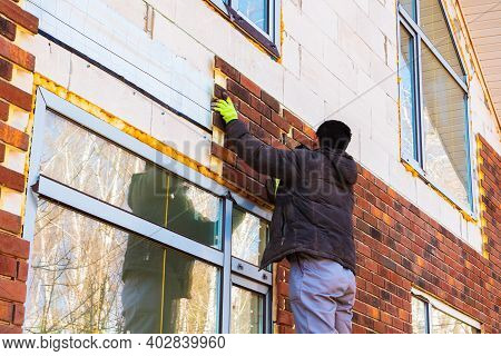 A Man Works With A Drill, Attaches Thermal Panels Made Of Clinker To The Facade Of The House. Clinke