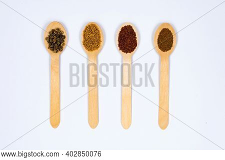 Various Seeds In Wooden Spoons On A White Background. Seeds Of Beet, Mustard, Lettuce, Arugula, On A