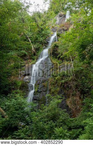 Long Exposure Of The Waterfall Flowing Over The Cliff At Canonteign Falls In Dartmoor
