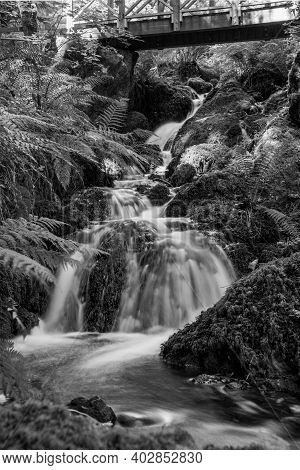 Long Exposure Of A Waterfall Flowing Under A Bridge At Canonteign Falls In Dartmoor