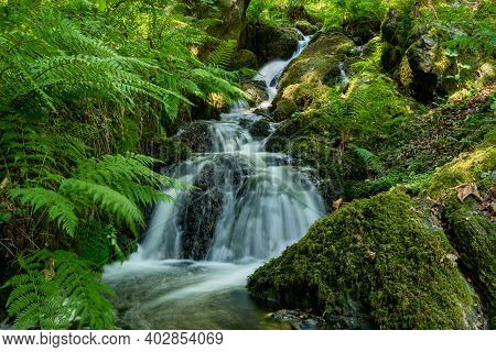 Long Exposure Of A Waterfall Flowing Through The Woods At Canonteign Falls In Dartmoor