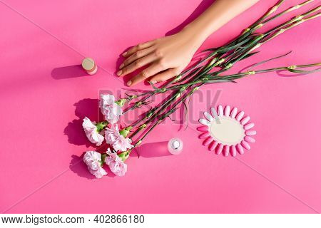 Top View Of Carnation Flowers Near Female Hand, Palette Of Artificial Nails, Nail Polish And Cuticle