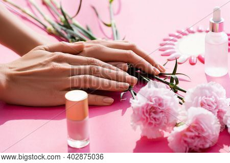 Cropped View Of Female Hands Near Carnation Flowers, Bottles Of Nail Polish And Cuticle Remover, And