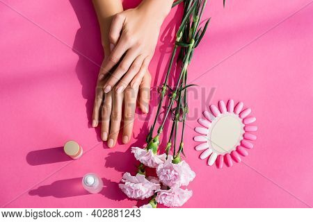 Top View Of Female Hands Near Palette Of Fake Nails, Carnation Flowers, Cuticle Remover And Nail Var