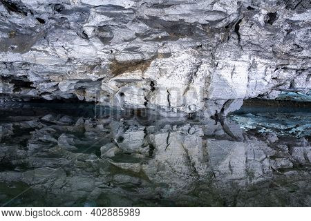 Underground Lake Inside The Ice Cave. Slope Of The Mountain With The Reflection In The Water Inside 