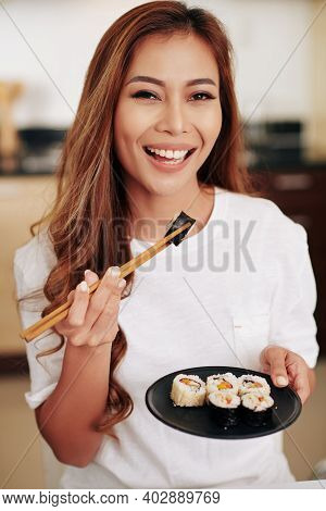 Portrait Of Attractive Young Asian Woman With Chopstics Eating Plate With Delicious Sushi