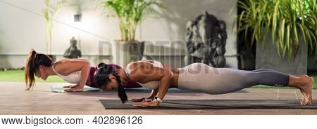 Panorama Two asian women in sportswear pants practicing yoga during city lockdown in their apratment with background of cityscape illumination at night. Work out fitness healthy lifestyle concept.