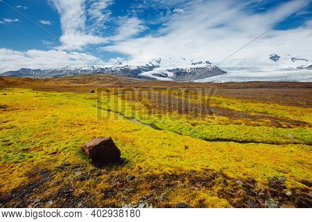 Sunny landscape of snowy mountains and green valley. Location place Oraefajokull glacier, Vatnajokull National Park, Iceland, Europe. Image of exotic world landmarks. Discover the beauty of earth.