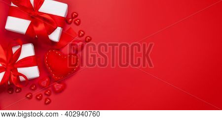 Valentines day greeting card template. Gift boxes, heart decor and candy sweets over red background. Top view flat lay with copy space