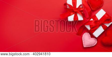 Valentines day greeting card template. Gift boxes and heart shaped decor over red background. Top view flat lay with copy space