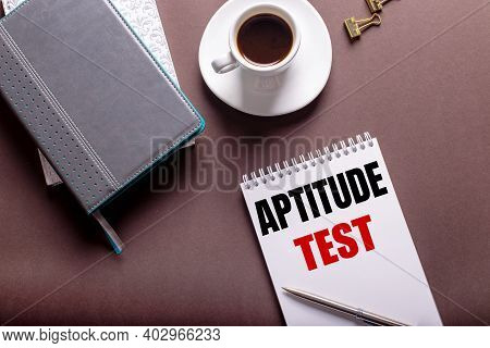 On A Brown Background, Diaries, A White Cup Of Coffee And A Notebook With Aptitude Test.