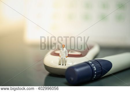 Docter Miniature Figure People Standing On Glucose Meter With Lancet And Calendar As Background. Use
