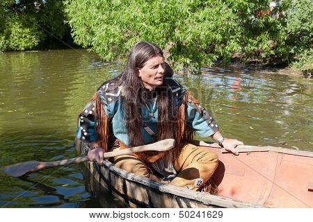 North American Indian floats down the river on a canoe