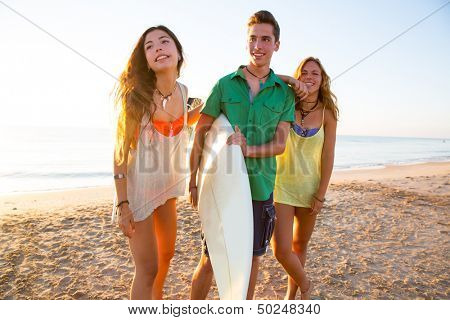 Surfer girls with teen boy walking on beach shore high key