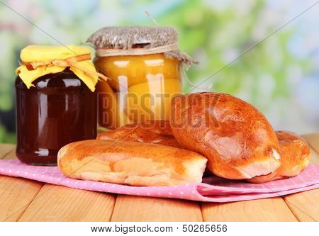 Fresh baked pasties with fruit jam, on wooden table, on bright background