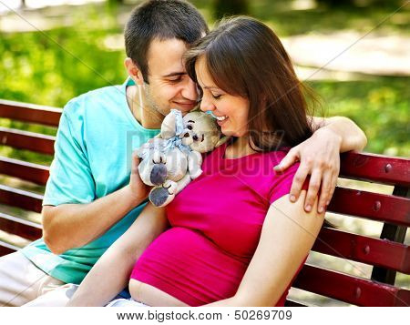 Pregnant woman, holding flower with man  outdoor in park.