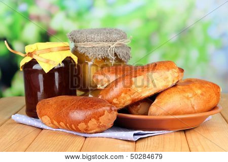 Empanadas al horno frescas con mermelada de frutas, en mesa de madera, sobre fondo brillante