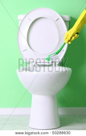 Kvinde hånd med pensel rengøring et toilet skål i et badeværelse
