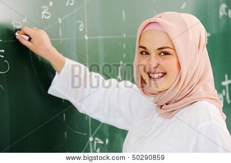 Arabské muslimské dospívající student uvnitř střední školy ve třídě pózuje na palubě