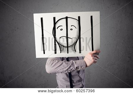 Businessman holding a paper with a prisoner in jail behind the bars on it in front of his head