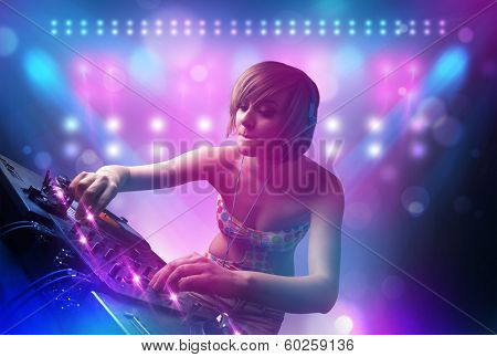 Pretty young disc jockey mixing music on turntables on stage with lights and stroboscopes