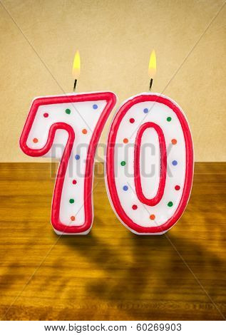 Burning birthday candles number 70 on a wooden background