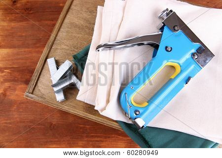 Construction stapler with fabrics and staples on wooden background