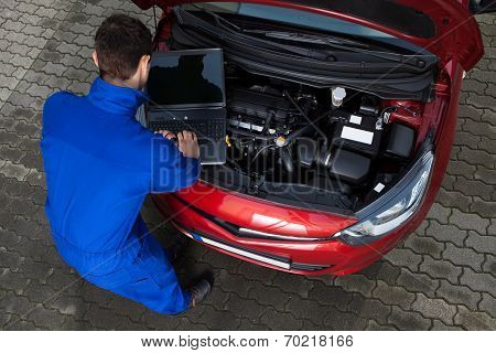 Mechanic Using Laptop While Repairing Car