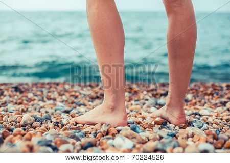 The Feet Of A Young Woman Standing On The Beach