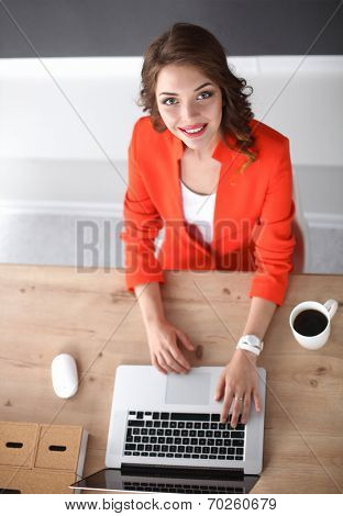 Attractive woman sitting at desk in office, working with laptop
