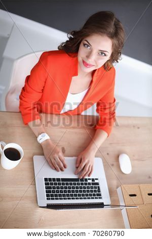 Attractive woman sitting at desk in office, working with laptop