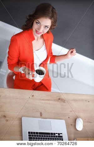 Attractive woman sitting at desk in office, working with laptop