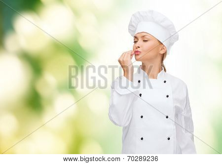 cooking, gesture and food concept - smiling female chef showing delicious gesture