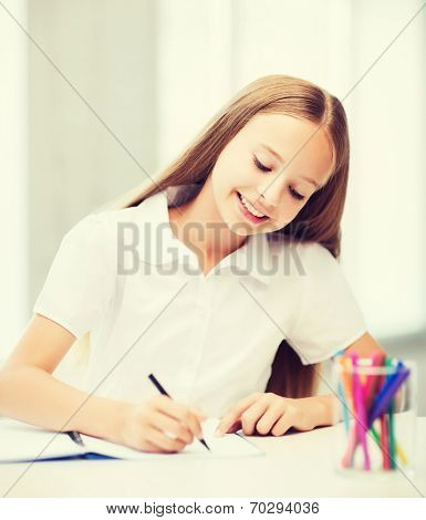 education and school concept - little student girl drawing at school