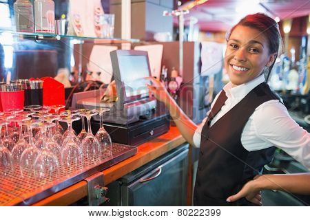 Pretty barmaid using touchscreen till in a bar