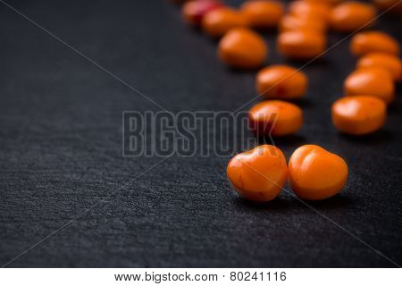Orange heart shaped pills or candy on grunge black slate background. Copy space.