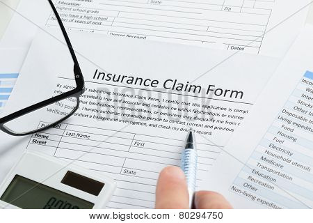 Hand With Pen On Insurance Claim Form