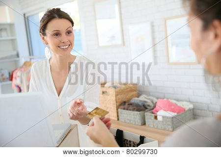 Customer in clothing store giving credit card to seller
