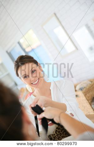 Seller in clothing store giving bag to customer
