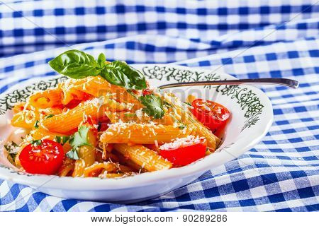 Plate with pasta pene Bolognese sauce cherry tomatoes parsley top and basil leaves