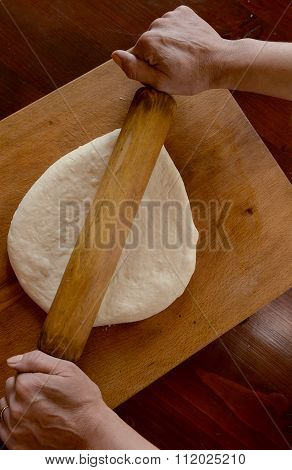 Sheeting dough. Women's hands are holding rolling pin